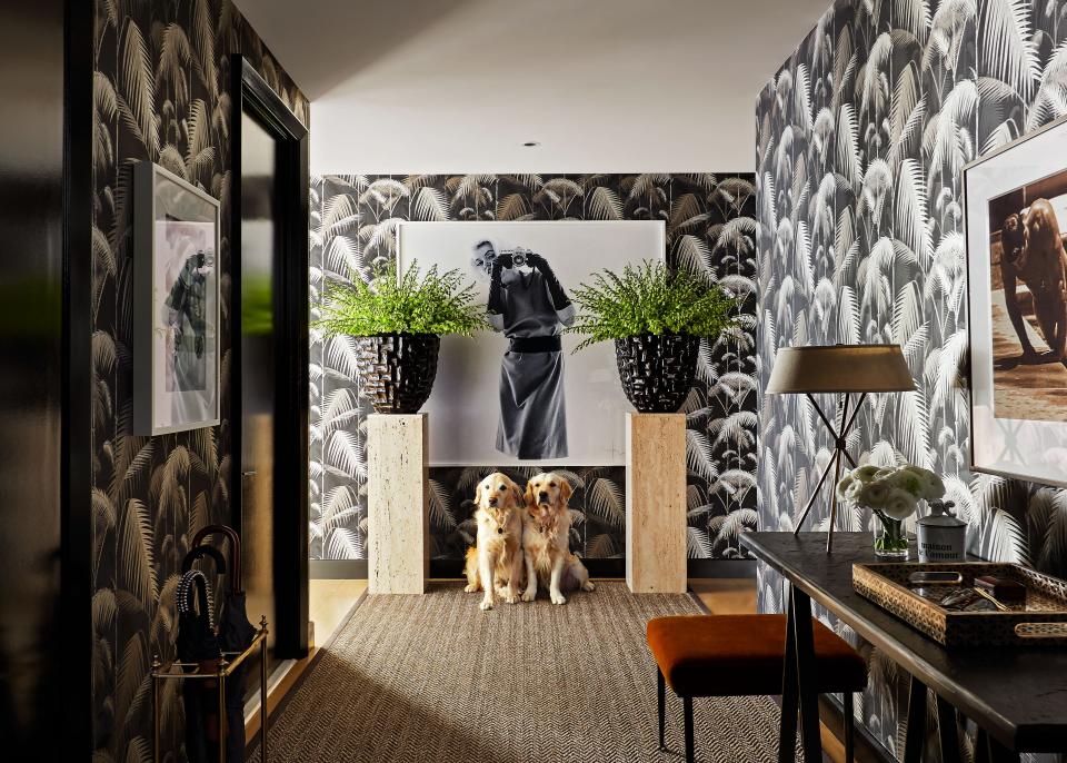 “The whole apartment is basically glass walls, so we wanted the entrance to feel cozy and intimate,” says Deutsch. “We painted the moldings and all of the doors this high-gloss black so you’d have that juxtaposition with the light as you turn the corner. We’re not afraid of the wow factor.” Oversize planters sit on travertine pillars and flank a Bert Stern photo of Marilyn Monroe. The palm jungle wallpaper is from Cole and Son and the ottoman is by Christian Liaigre.