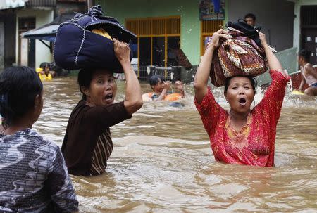 Women react as they flee from their flooded area in Jakarta in this January 17, 2013 file photo. REUTERS/Enny Nuraheni/Files