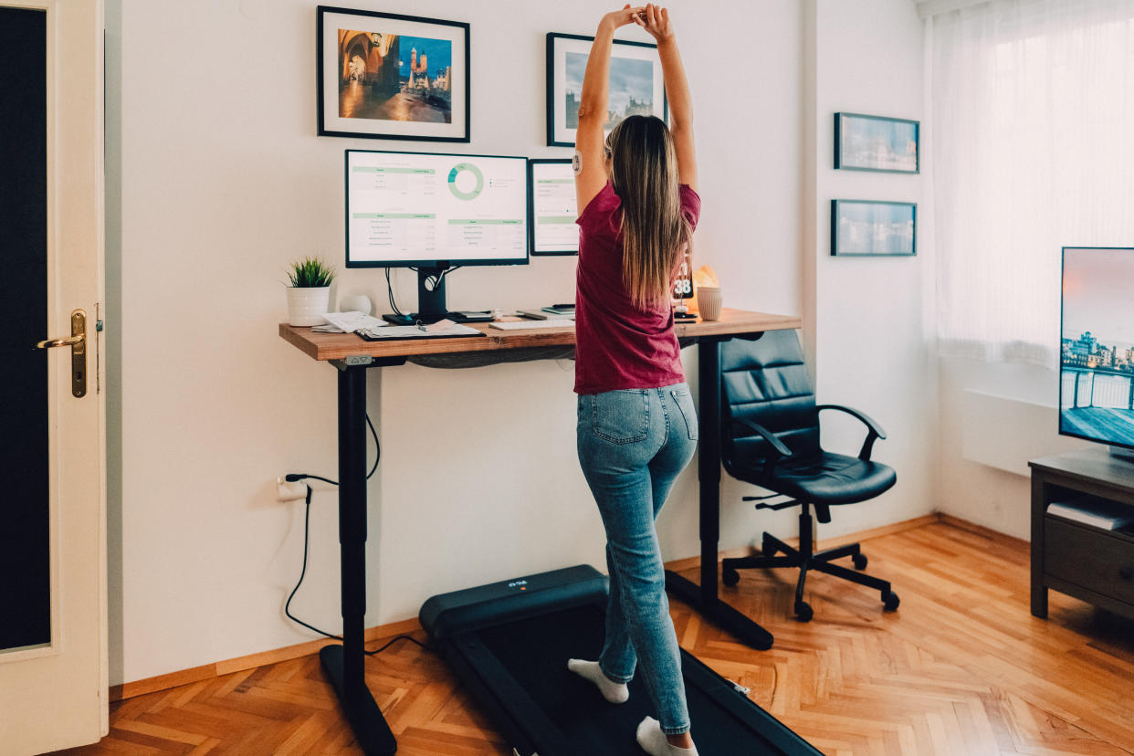 amazon walking pad: woman working from home at standing desk is walking on under desk walking pad treadmill