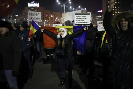 A protester holds Romanian national flags during a demonstration in Bucharest, Romania, February 3, 2017. REUTERS/Stoyan Nenov