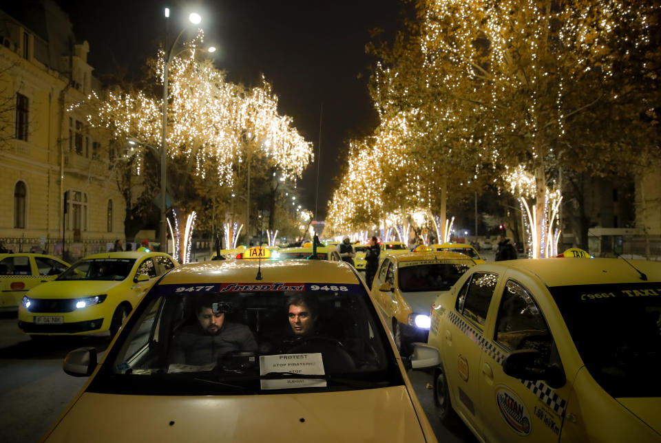 FILE - In this Monday, Jan. 21, 2019, file photo taxi drivers block a main boulevard during a protest against ride hailing services in Bucharest, Romania. The Romanian government has issued an emergency decree ramping up steep fines for drivers of ride-hailing services like Uber and Taxify. The decree taking effect Thursday, May 16, 2019 fines drivers transporting people in their car without a valid taxi license up to $1,175 (1,050 euros) already from the first offense. Previously, drivers were fined only after repeated offenses. (AP Photo/Vadim Ghirda, File)