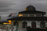 Hot lava runs down from the crater of Mount Merapi, partially seen behind a mosque in Sleman, Indonesia, late Tuesday, Jan. 26, 2021. The country's most active volcano erupted Wednesday with a river of lava and searing gas clouds flowing 1,500 meters (4,900 feet) down its slopes. (AP Photo/Slamet Riyadi)