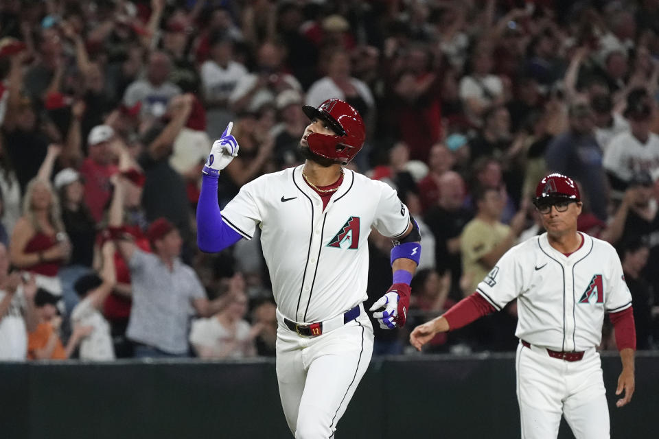 Arizona Diamondbacks' Lourdes Gurriel Jr., left, celebrates his two-run home run against the Colorado Rockies as third base coach Tony Perezchica, right, watches during the first inning of a baseball game Thursday, March 28, 2024, in Phoenix. (AP Photo/Ross D. Franklin)