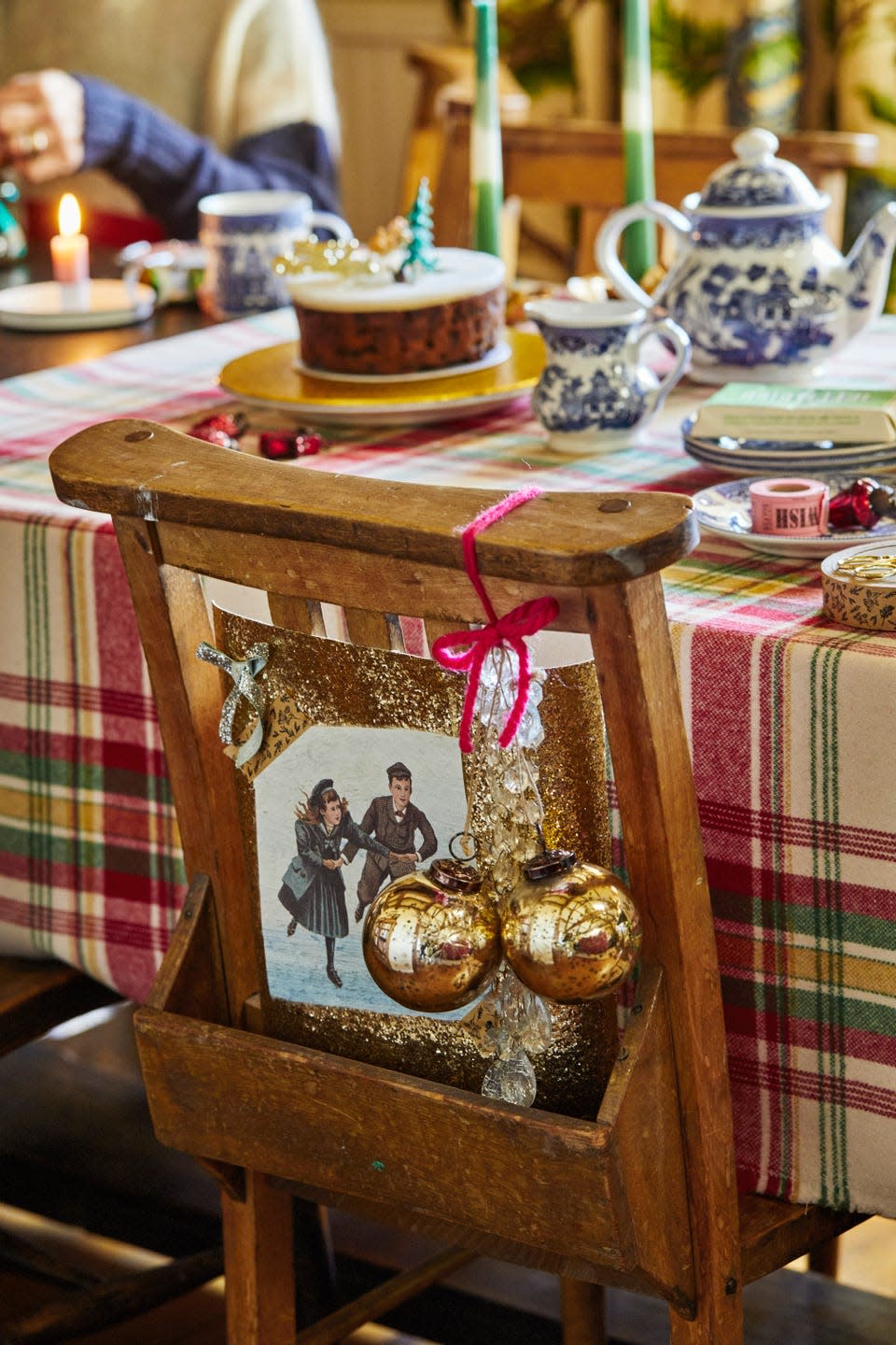 a table laid with christmas decor and gold baubles hanging from a dining room chair