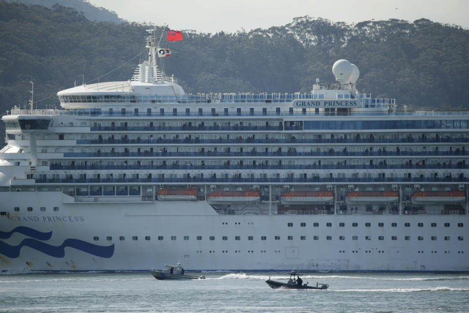 A pair of boats escort the Grand Princess cruise ship through San Francisco Bay Monday, March 9, 2020, in this view from Sausalito, Calif. The cruise ship carrying at least 21 people infected with the coronavirus passed under the Golden Gate Bridge as federal and state officials in California prepared to receive thousands of people on the ship that has been idling off the coast of San Francisco. Personnel covered head to toe in protective gear Monday woke up passengers on the Grand Princess to check whether they were sick. (AP Photo/Eric Risberg)