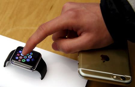 A customer holding his iPhone touches an Apple Watch after it went on display at the Sydney Apple store April 10, 2015. REUTERS/David Gray