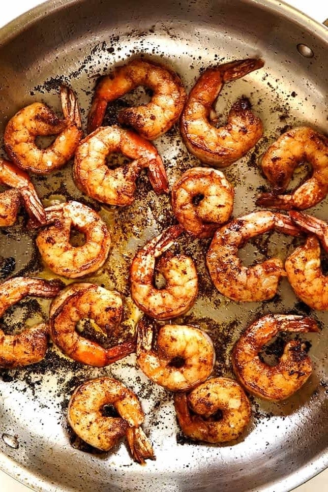 A pan filled with cooked shrimp seasoned with spices