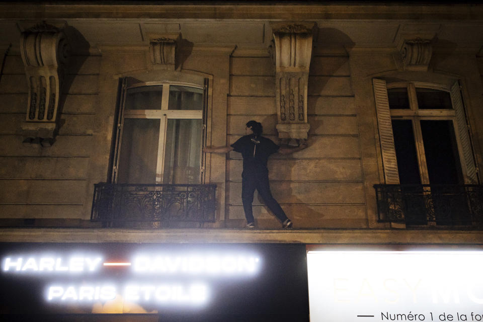An activist from the collective "On the Spot" climbs up a building as they attempt to extinguish the lights on dozens of storefronts in Paris, Friday, July 29, 2022. The collective had been acting against wasteful businesses in Paris long before Russia started cutting energy supplies to Europe in a battle of wills over Moscow's invasion of Ukraine. As such, the campaigners were precursors of the energy economy drive becoming all the rage in France, Germany and elsewhere. (AP Photo/Lewis Joly)