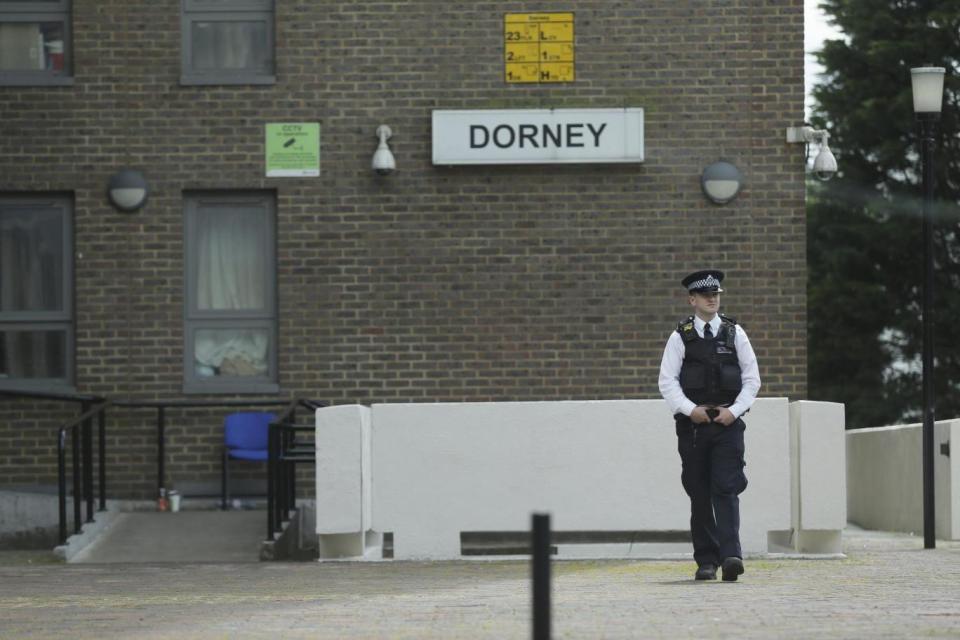 A police officer stands outside Dorney Tower, part of the Chalcots Estate (AP)