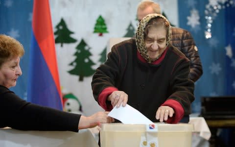 A woman casts her ballot during early parliamentary elections in Yerevan - Credit: KAREN MINASYAN/AFP/Getty Images