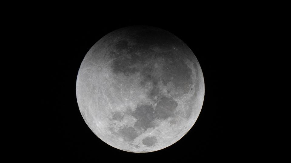  The top edge of the moon darkened by a shadow. 