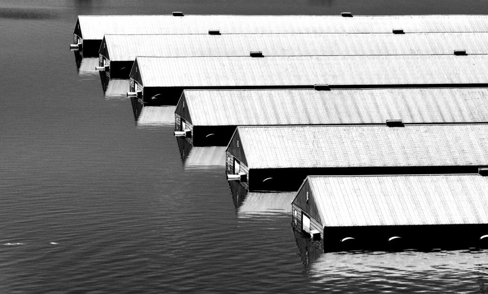 Rows of long, low buildings are surrounded by water.