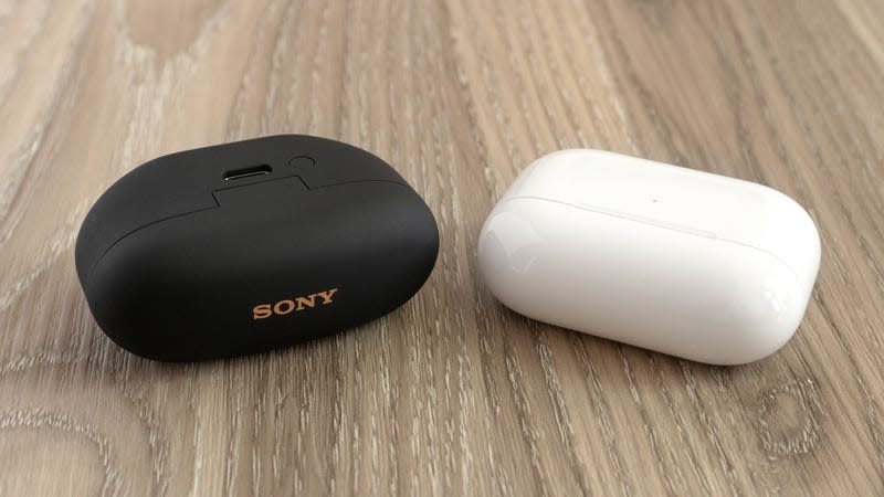 The Sony WF-1000XM5s’ charging case (left) is nearly identical in size to the Apple AirPods Pro 2's charging case (right), but can be charged using a USB-C cable instead of a Lightning cable. - Photo: Andrew Liszewski | Gizmodo