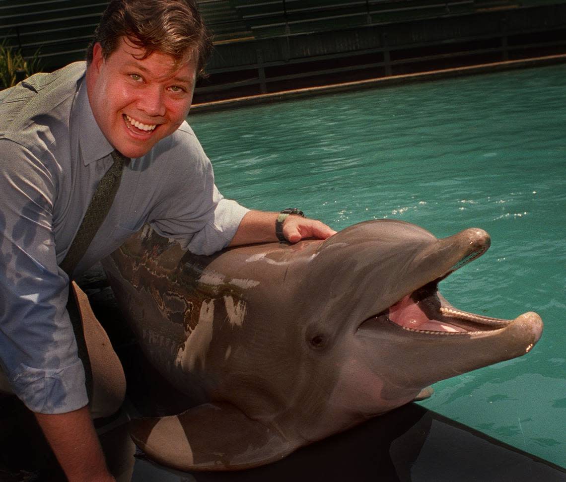Miami Seaquarium executive Andrew Hertz cuddles with Sundance, an Atlantic bottlenose dolphin performing in the Flipper Show.