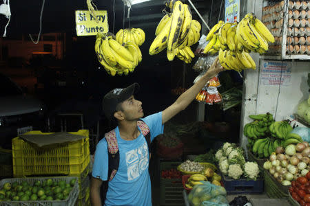 Marlon Carrillo buys fruits to resell them in Colombia, at a market in Rubio, Venezuela December 15, 2017. REUTERS/Carlos Eduardo Ramirez