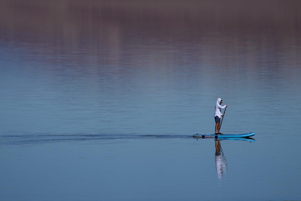 A paddle boarder paddles through water Thursday at Badwater Basin in Death Valley National Park, Calif. Kayakers and visitors have flocked to the park to take advantage of the ephemeral waters that have filled the basin, which is normally a dry salt flat.