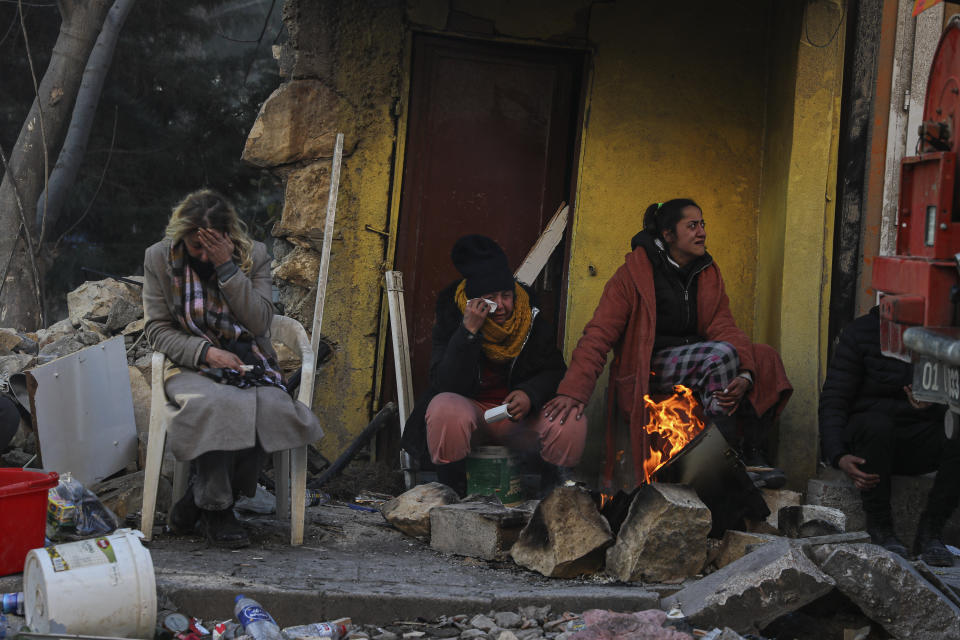 People sit by the debris of their collapsed house in Hatay, southern Turkey, Thursday, Feb. 9, 2023. Emergency crews made a series of dramatic rescues in Turkey on Friday, pulling several people, some almost unscathed, from the rubble, four days after a catastrophic earthquake killed more than 20,000. (AP Photo/Can Ozer)