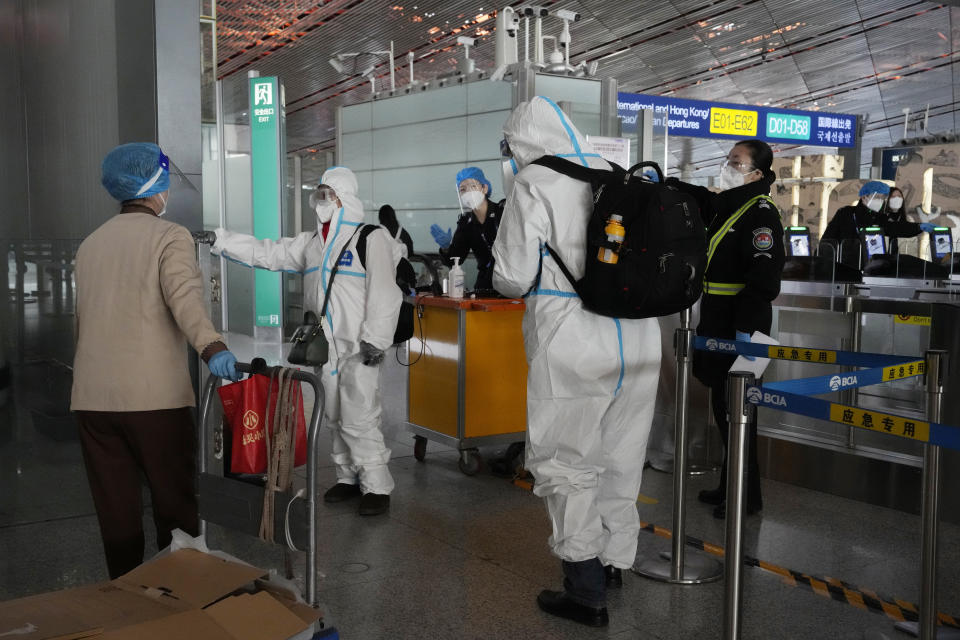 Passengers in protective gear are directed to a flight at a Capital airport terminal in Beijing, Tuesday, Dec. 13, 2022. Some Chinese universities say they will allow students to finish the semester from home in hopes of reducing the potential of a bigger COVID-19 outbreak during the January Lunar New Year travel rush. (AP Photo/Ng Han Guan)