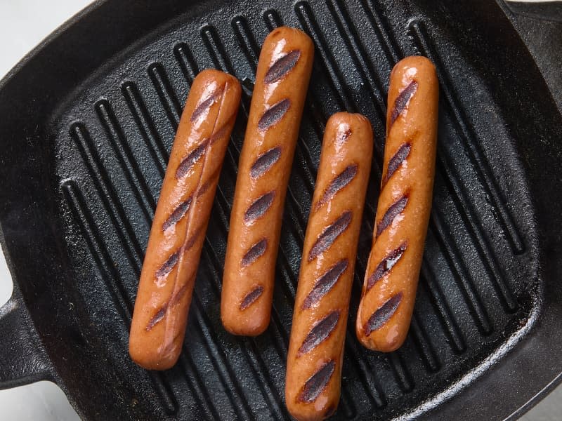 overhead photo of hot dogs cooked in a cast iron grill pan