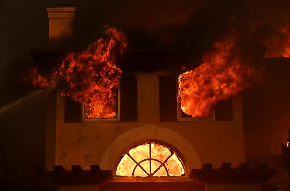 Flames burst through the windows of a home.
