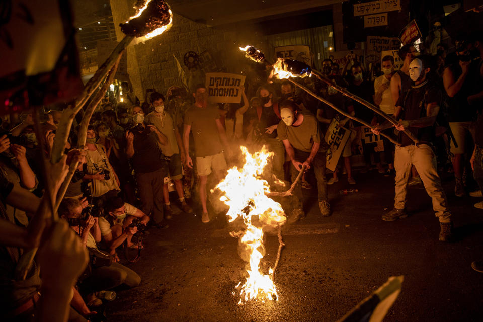 Protesters light torches during a protest against Israel's Prime Minister Benjamin Netanyahu outside his residence in Jerusalem, Saturday, Aug 1, 2020. Protesters demanded that the embattled Israeli leader to resign as he faces a trial on corruption charges and grapples with a deepening coronavirus crisis. (AP Photo/Oded Balilty)