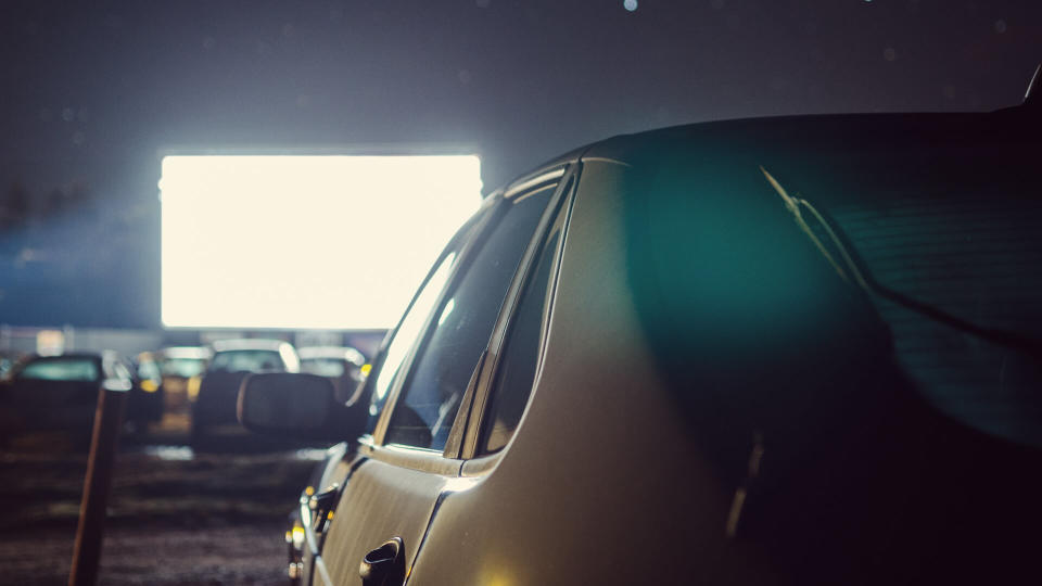 A parked car at a drive-in movie theater.