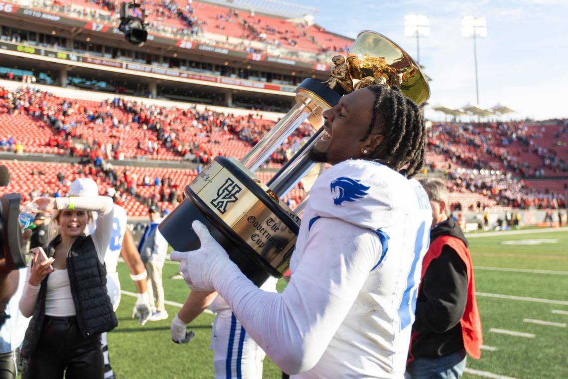 Kentucky rush end/outside linebacker J.J. Weaver (13) celebrates with the Governor’s Cup trophy after the Wildcats upset Louisville 38-31 in the regular-season finale.