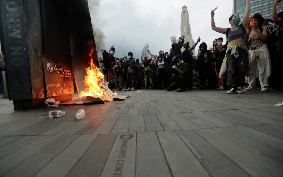 Protesters set a fire as they rally at the Barclays Center - AP