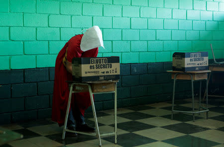 An activist dressed in a costume from The Handmaid's Tale series prepares to cast a ballot during the presidential election, at a polling station in San Jose, Costa Rica, April 1, 2018. REUTERS/Juan Carlos Ulate