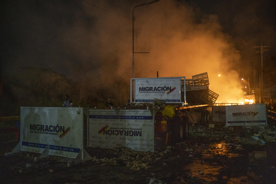 A truck previously loaded with humanitarian aid is in flames behind immigration barricades scattered across the Francisco De Paula Santander International Bridge. (Photo: Federico Rios/Bloomberg via Getty Images)