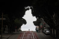 Pedestrians cross Cable Car tracks on Powell Street in San Francisco, Sunday, March 29, 2020. Californians endured a weekend of stepped-up restrictions aimed at keeping them home as much as possible while hospitals and health officials scrambled Sunday to ready themselves for a week that could see the feared dramatic surge in coronavirus cases. (AP Photo/Jeff Chiu)