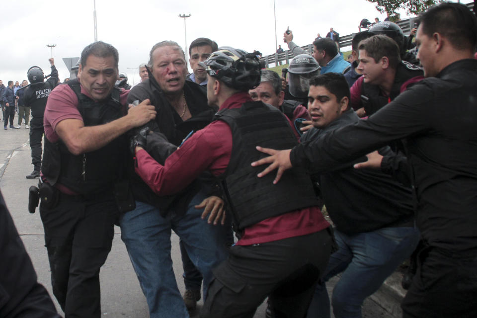 Sergio Berni, the security minister for the Buenos Aires province, center, is extracted from a protest in Buenos Aires, Monday, April 3, 2023. Berni was attacked during a protest by bus drivers after the murder of a co-worker while on the job. (AP Photo/Andres Pelozo)