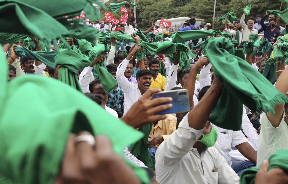 Indian farmers raise their shawls and shout anti-government slogans during a protest against farm bills in Bengaluru, India, Monday, Sept. 21, 2020. (AP Photo/Aijaz Rahi)