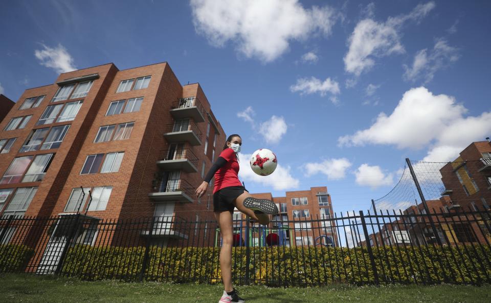 Wearing a face mask, Venezuelan soccer player María Alejandra Peraza, who played last season with Colombia's Millonarios women's team, trains in Bogota, Colombia, Thursday, May 21, 2020. Peraza is one of hundreds of professional female players who have received a food package from the Ministry of Sport in Colombia during the lockdown to curb the COVID-19. (AP Photo/Fernando Vergara)