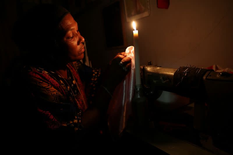 FILE PHOTO: Dressmaker Faieza Caswell from Mitchells Plain sews under candlelight in her workplace, in Cape Town