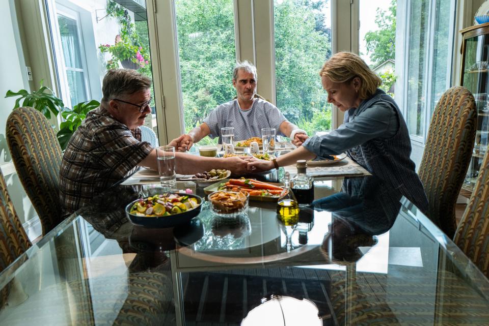 After getting hit by a truck, Beau (Joaquin Phoenix, center) is taken in by a suspiciously kind suburban couple (Nathan Lane and Amy Ryan) in the dark comedy "Beau Is Afraid."