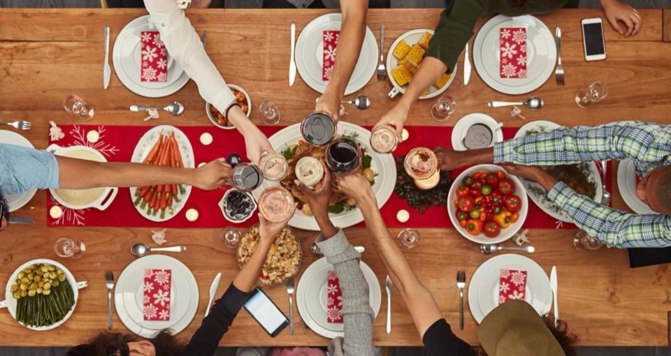 Aerial view of people at Christmas meal raising their glasses to a toast