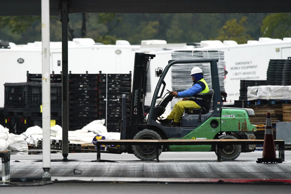 Workers disassemble hangar-sized tents, Tuesday, Oct. 4, 2022, in the parking lot of Orchard Beach in the Bronx borough of New York. Giant tents for temporarily housing migrants arriving in New York City are being moved to an island off Manhattan from a remote corner of the Bronx, after storms raised concerns over flooding at the original site. (AP Photo/Julia Nikhinson)