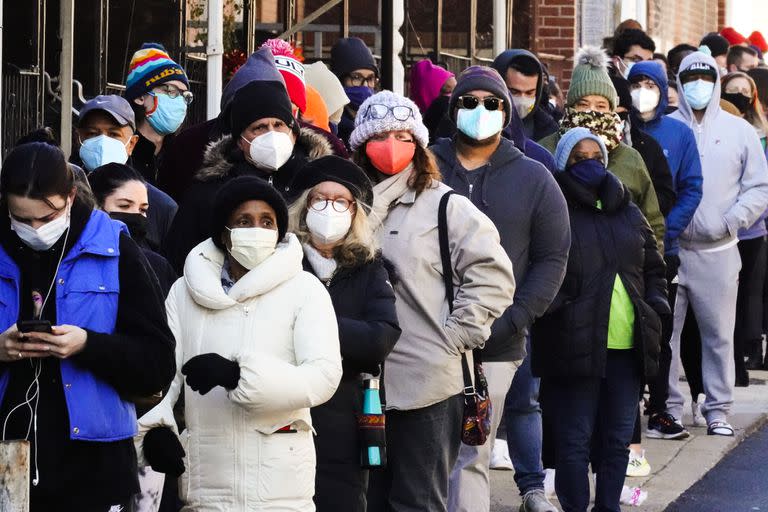 Decenas de residentes de la ciudad hacen una fila que se extiende alrededor de la cuadra para recibir kits gratuitos de prueba rápida de COVID-19 en el hogar, el lunes 20 de diciembre de 2021 en Filadelfia