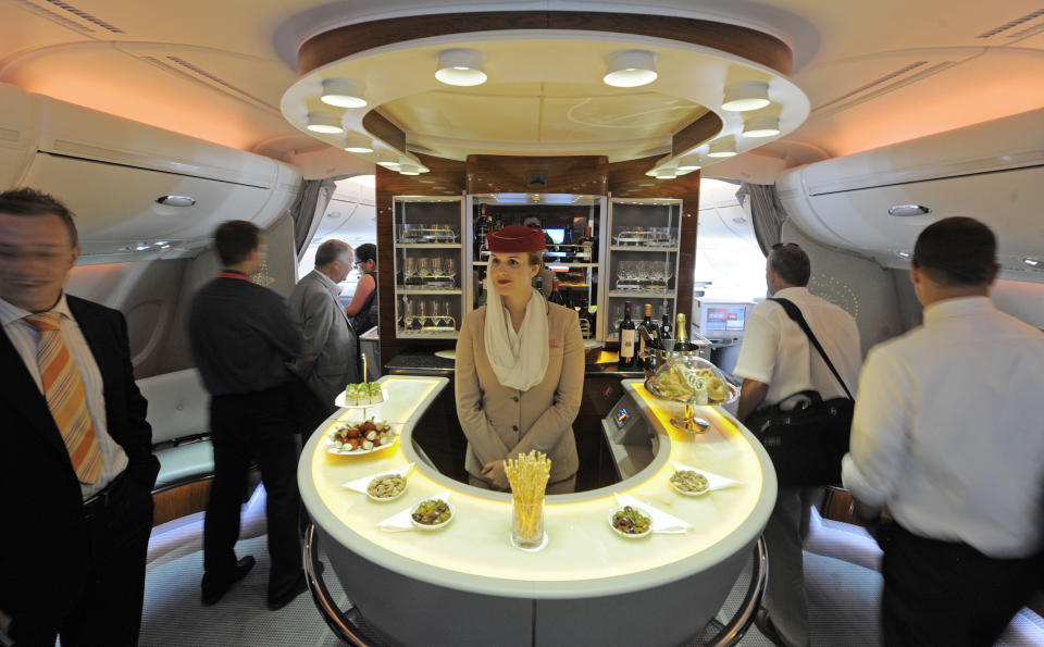 FILE- In this July 13, 2010, file photo Nadine Schumacher, center, works at the bar in the first class section on board Airbus A380 passenger plane of Emirates Airline during the International Air Show ILA at Schoenefeld airport in Berlin. European plane maker Airbus said Thursday, Feb. 14, 2019, that it will stop making its superjumbo A380 in 2021 for lack of customers, abandoning the world's biggest passenger jet and one of the aviation industry's most ambitious and most troubled endeavors. (AP Photo/Jens Meyer, File)