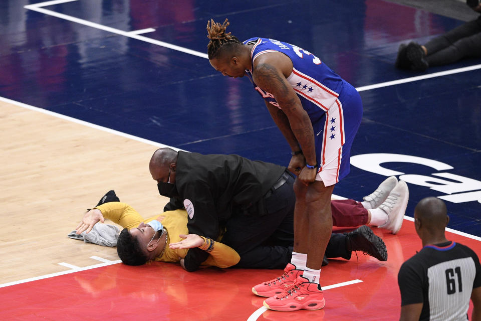 Philadelphia 76ers center Dwight Howard (39) watches as a fan who ran onto the court is restrained by security personnel during the second half of Game 4 in a first-round NBA basketball playoff series against the Washington Wizards, Monday, May 31, 2021, in Washington. (AP Photo/Nick Wass)