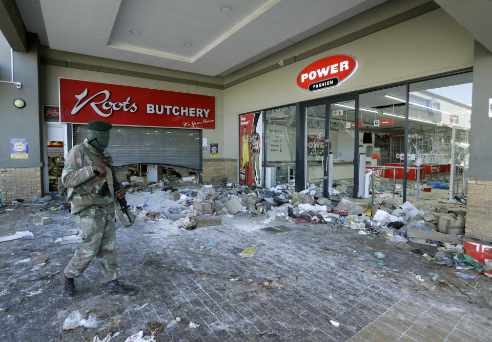 A patrolling soldier looks on at damaged stores at a shopping centre in Soweto near Johannesburg, Tuesday July 13, 2021 as ongoing looting and violence continues. South Africa's rioting continued Tuesday with the death toll rising to 32 as police and the military struggle to quell the violence in Gauteng and KwaZulu-Natal provinces. The violence started in various parts of KwaZulu-Natal last week when Zuma began serving a 15-month sentence for contempt of court. (AP Photo/Themba Hadebe)