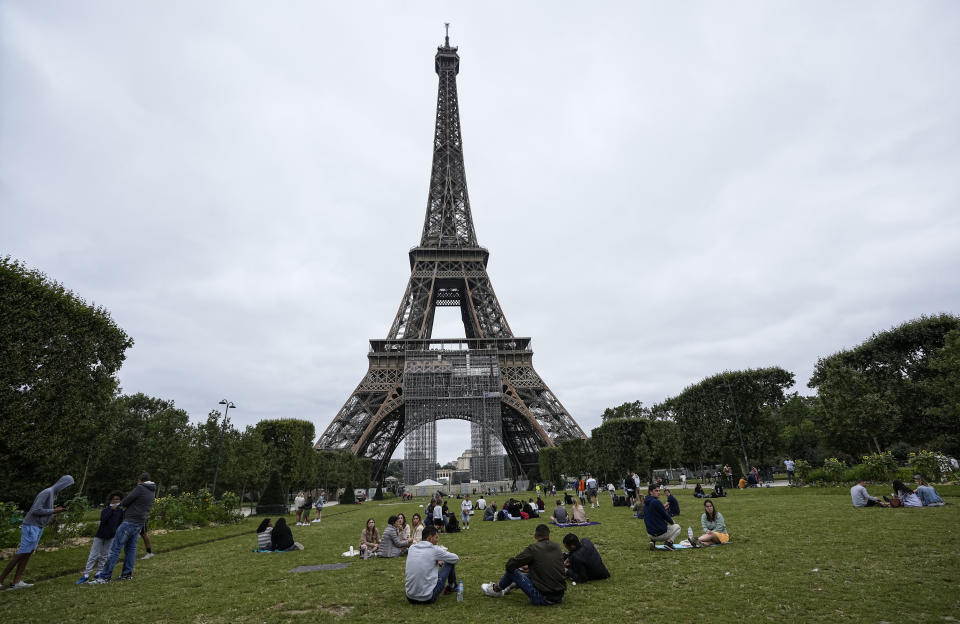 People relax at the Champ-de-Mars garden next to the Eiffel Tower in Paris, Friday, July 16, 2021. The Eiffel Tower is reopening Friday for the first time in nine months, just as France faces new virus rules aimed at taming the fast-spreading delta variant. The "Iron Lady" was ordered shut in October as France battled its second surge of the virus. (AP Photo/Michel Euler)