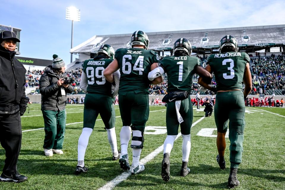 Michigan State senior captains, from left, Bryce Baringer, Jacob Slade, Jayden Reed and Xavier Henderson link arms as they make their way out for the coin toss before the game against Indiana on Saturday, Nov. 19, 2022, at Spartan Stadium in East Lansing.