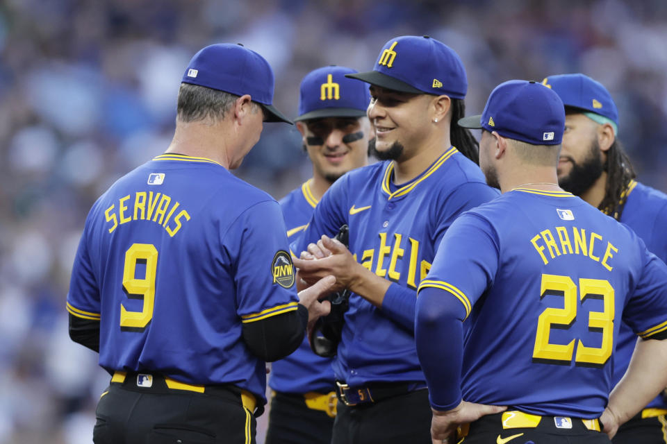 Seattle Mariners starting pitcher Luis Castillo, denter, smiles at manager Scott Servais (9) who asks for the ball to replace him during the seventh inning against the Toronto Blue Jays in a baseball game, Friday, July 5, 2024, in Seattle. (AP Photo/John Froschauer)