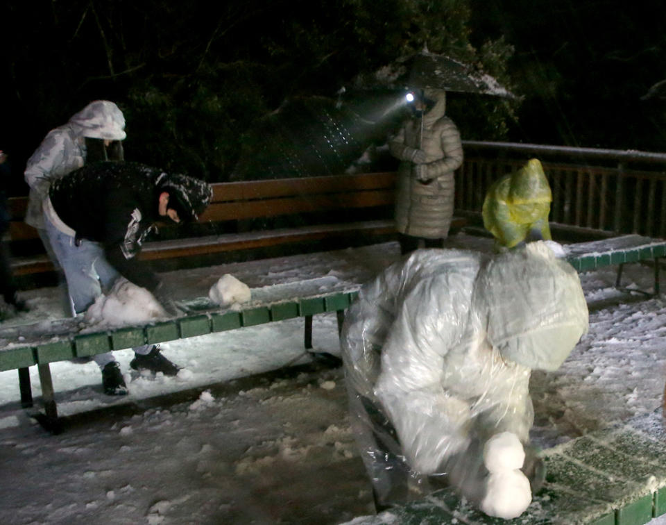 寒流發威配合豐沛水氣，陽明山的二子坪23日凌晨下起了冰霰，讓等待許久的民眾開心堆起雪人。（趙雙傑攝）