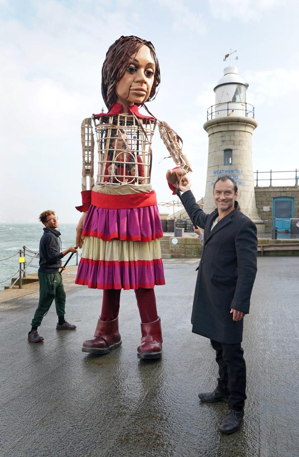 Actor Jude Law holds hands with Little Amal, a 3.5-metre-tall puppet of a nine-year-old Syrian girl, as it arrives in Folkestone, Kent, as part of the Handspring Puppet Company’s ‘The Walk’. Picture date: Tuesday October 19, 2021. (PA Wire)