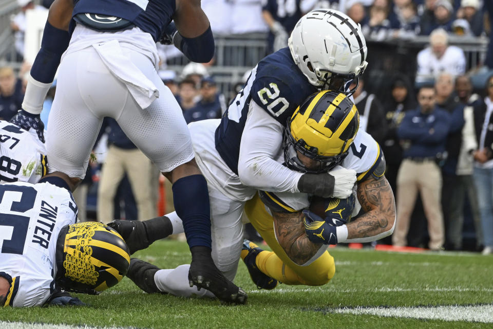 Michigan running back Blake Corum (2) scores a touchdown as Penn State defensive end Adisa Isaac (20) attempts to tackle him during the first half of an NCAA college football game, Saturday, Nov. 11, 2023, in State College, Pa. (AP Photo/Barry Reeger)