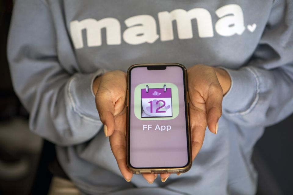 A woman holds a cellphone with a fertility app open