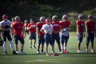 Simon Fraser University football team kicker Kristie Elliott, center, stands on the field with teammates during practice in Burnaby, B.C., Tuesday, Sept. 21, 2021. Elliott is enjoying her milestone in college football. Earlier this month, she became the first Canadian woman to play in an NCAA football game. (Darryl Dyck/The Canadian Press via AP)